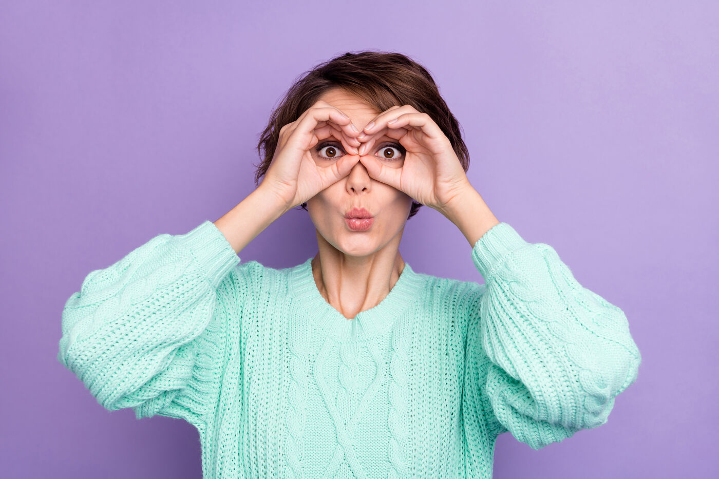Playful woman making binoculars with her hands, keeping an eye out for what is coming next